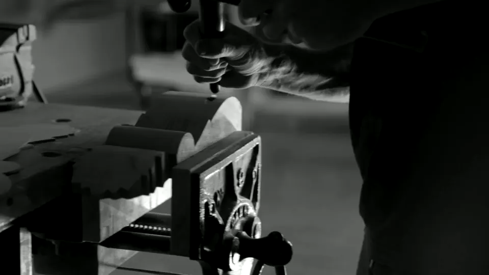 A person judging and shaping material at a workshop bench